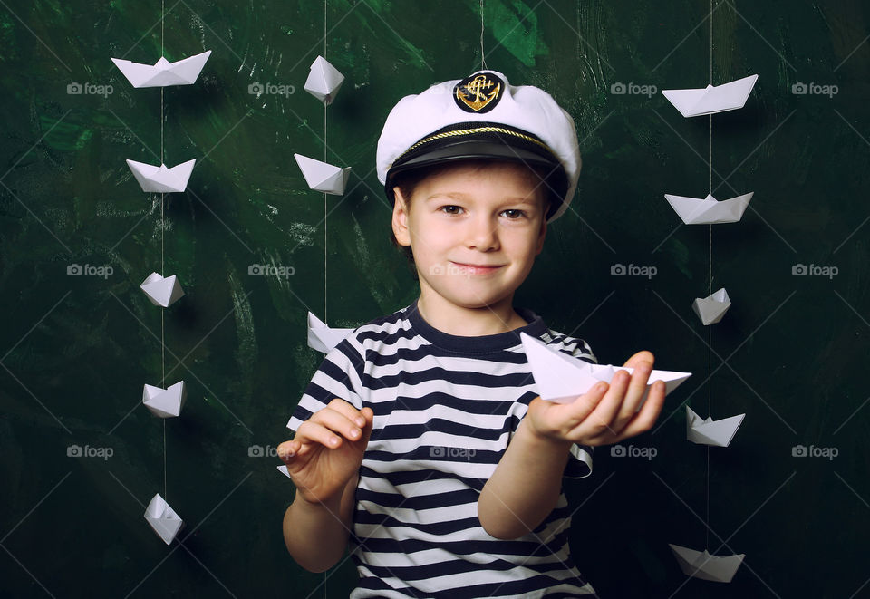 Little boy playing with paper boats at home, wants to be a sailor 