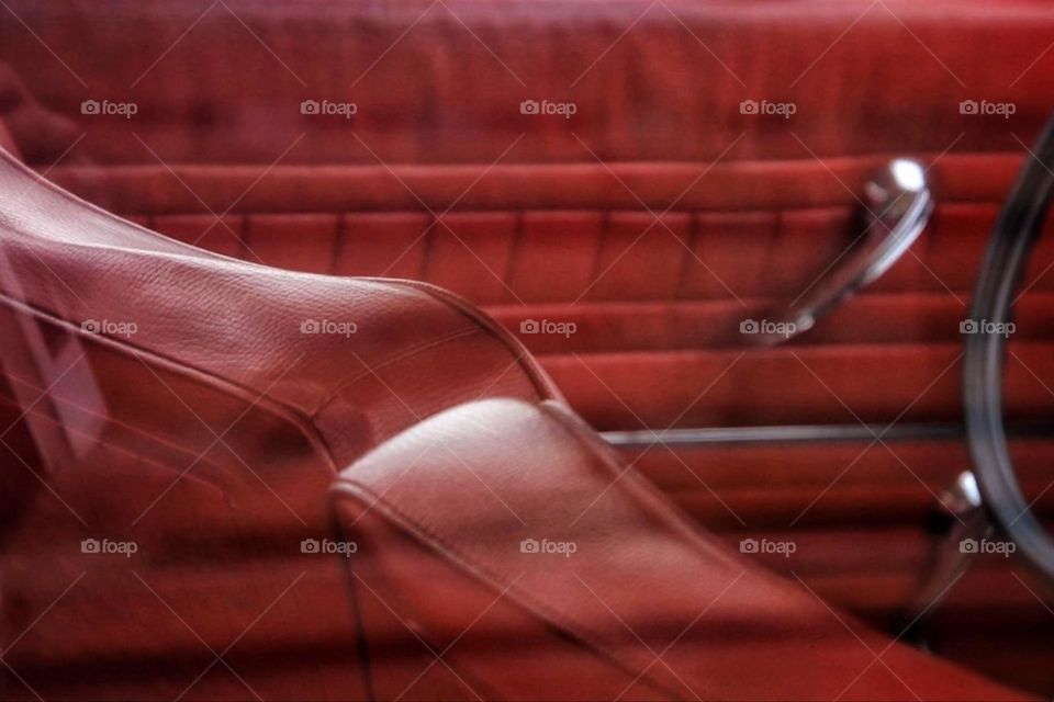 View through a car window of the beautiful dark red leather interior of a classic car