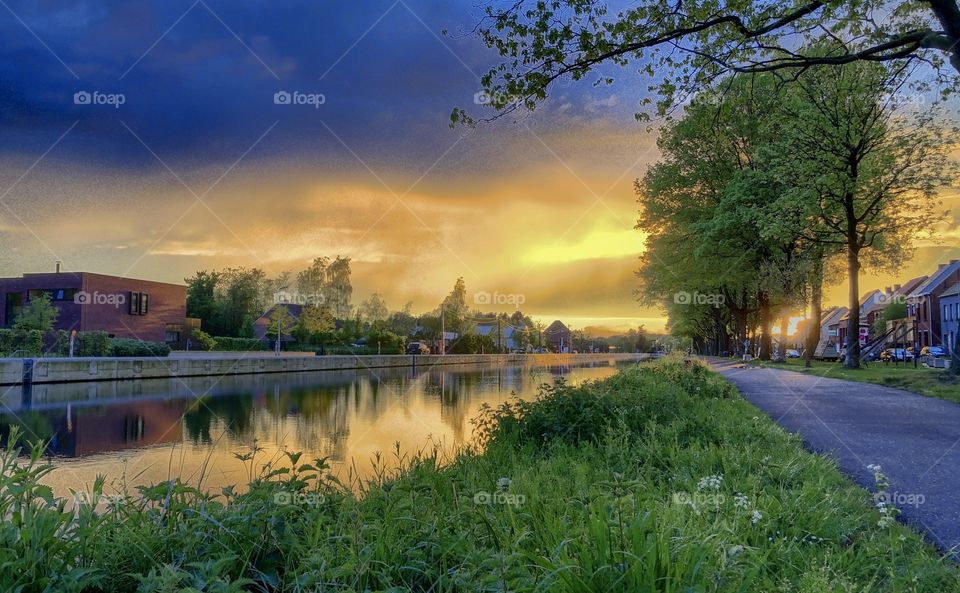 Colorful and dramatic sunrise or sunset over a Countryside river landscape seen from the riverside 