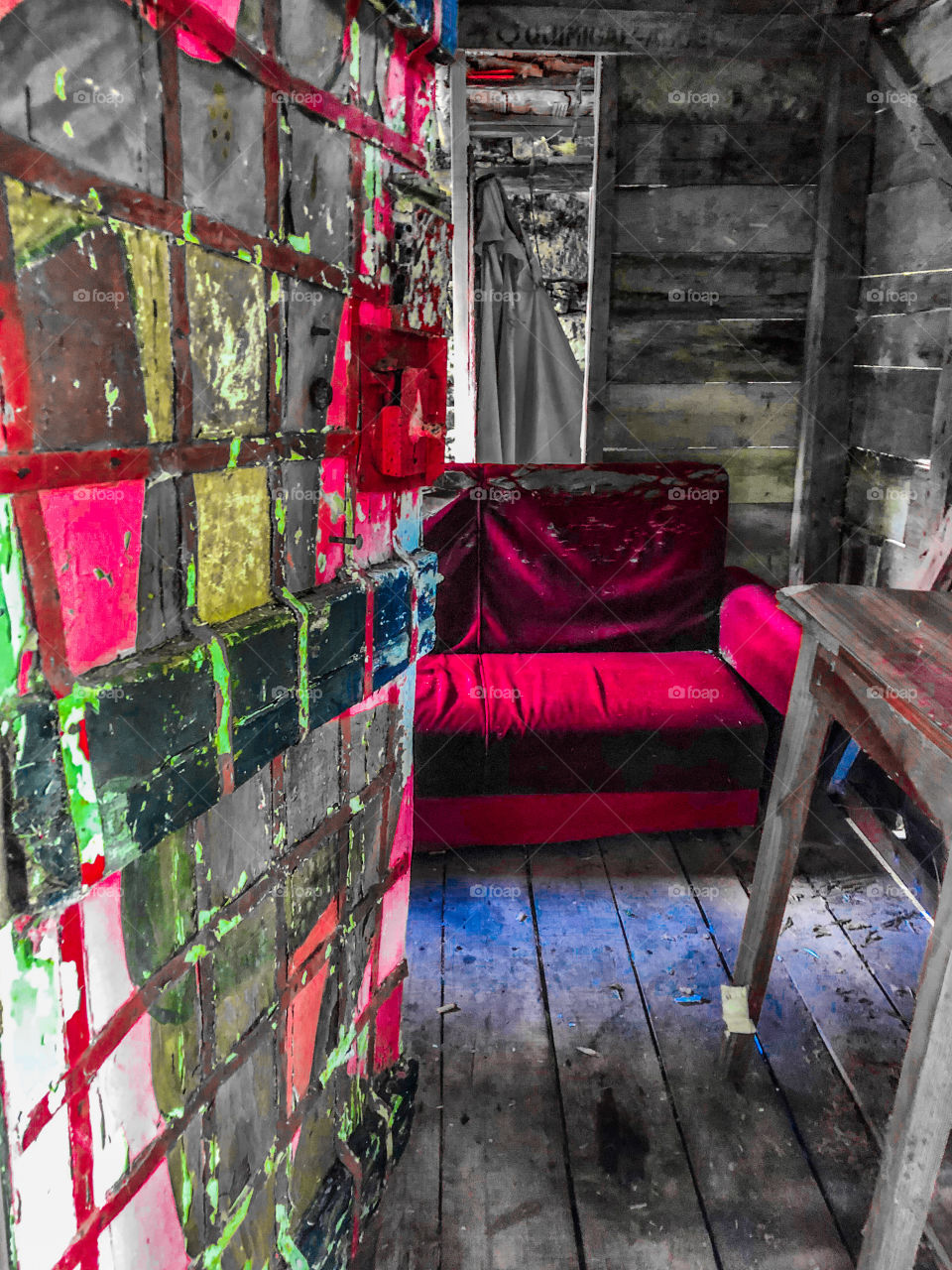 Peeking into an abandoned wood cabin, painted poorly with bright colours and equipped with a red velvet sofa