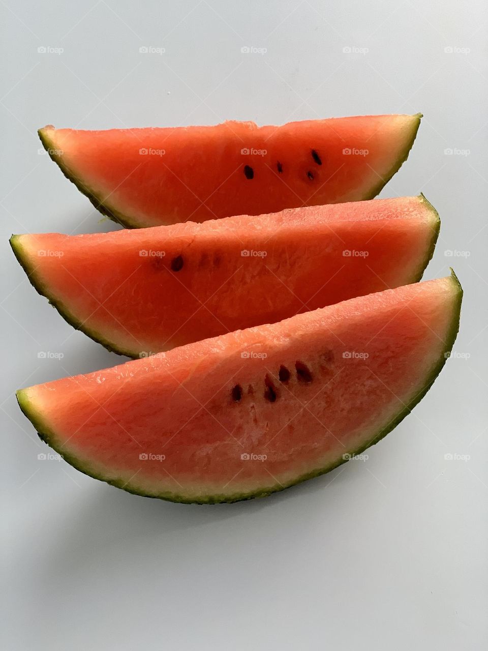 Slices of red watermelon with seeds against clear background 