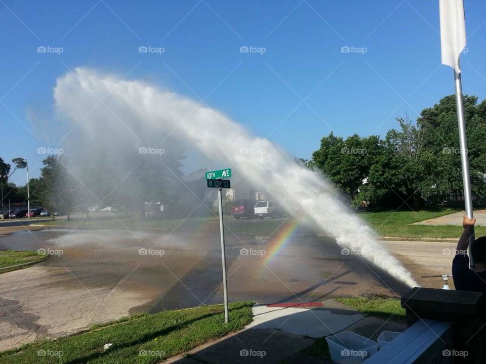 Fire hydrant and a rainbow on a cloudless day