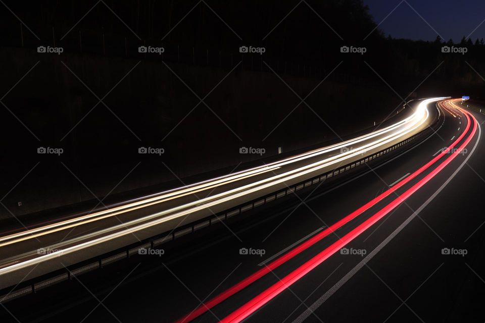 Red and white Light trails on highway curve created by long exposure of cars.