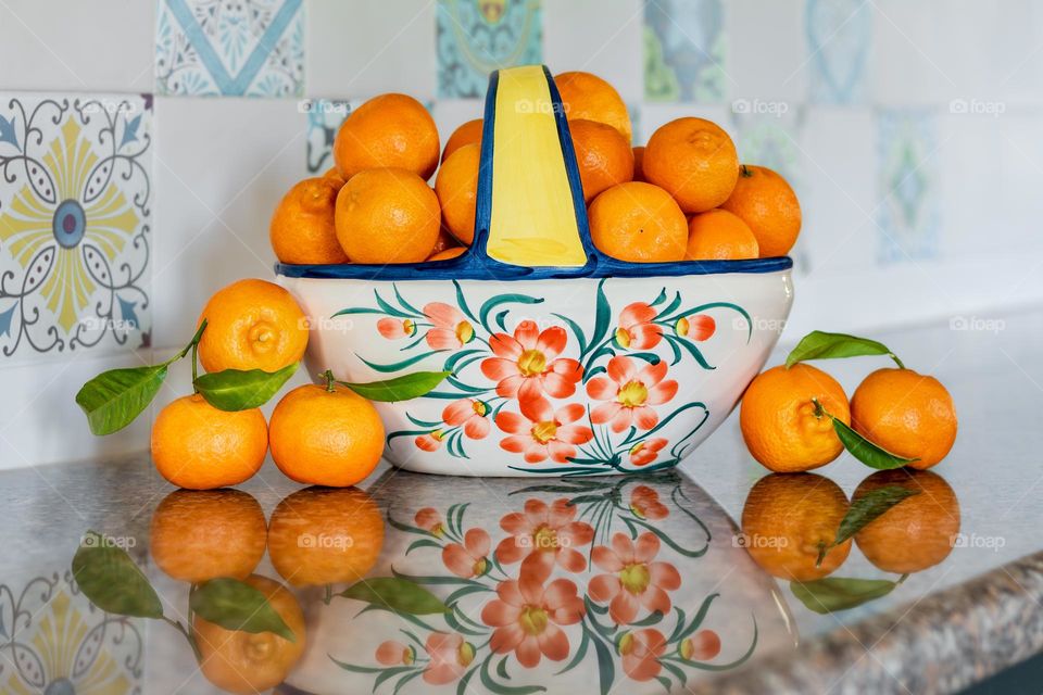 A fruit bowl full of oranges on a kitchen worktop.
