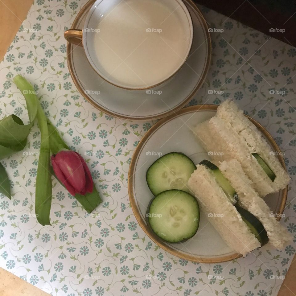 A cool crisp healthy cucumber sandwich displayed on a floral background with a tulip flower and a teacup. USA, America 