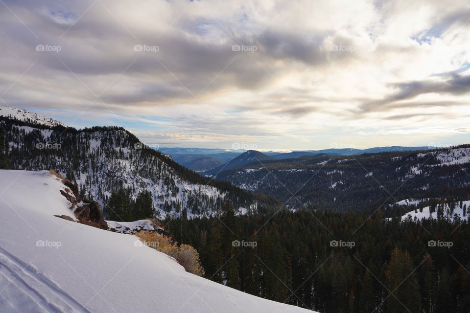 Peaceful landscape view of ski track on snow foreground and view of mountains and valley from the top of the mountain 