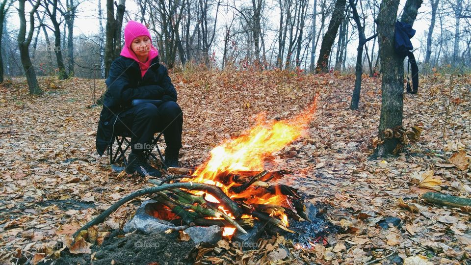 girl sitting by the fire on the nature, autumn 2016