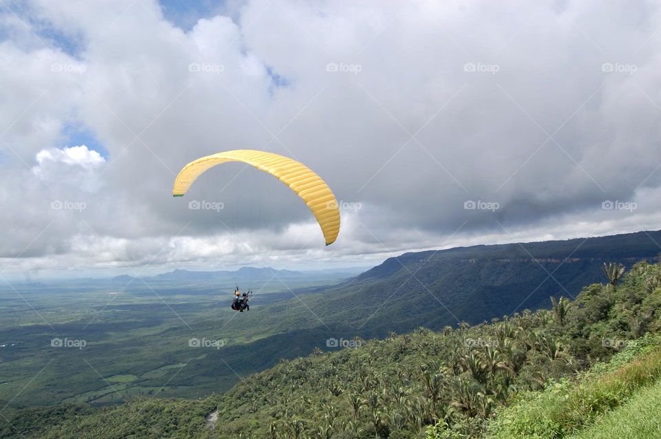 Paragliding over the green valley . 