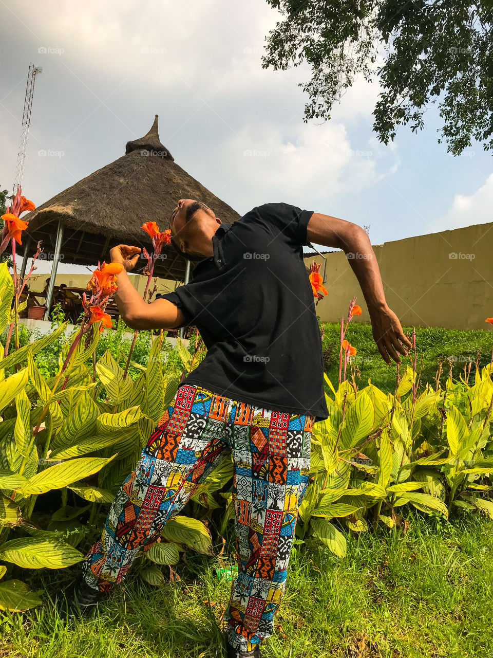 Man dancing in an african garden against bright blue sky 