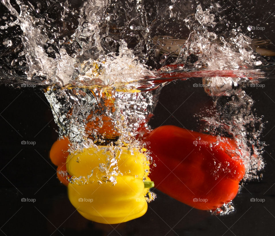 Colorful peppers splashing into water