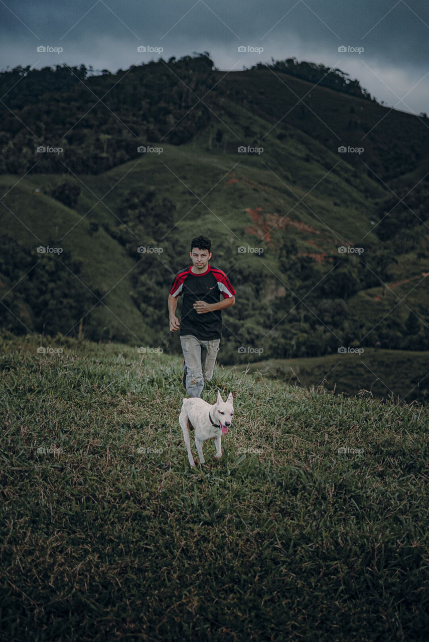 Man enjoying time with his best friend, boy running on the mountain with his pet