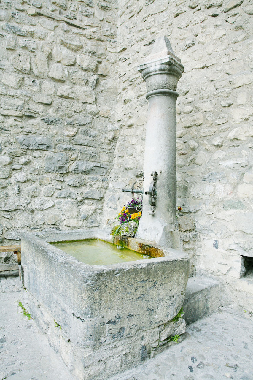 old stone fountain with watering in chateau chiilon, montreux,