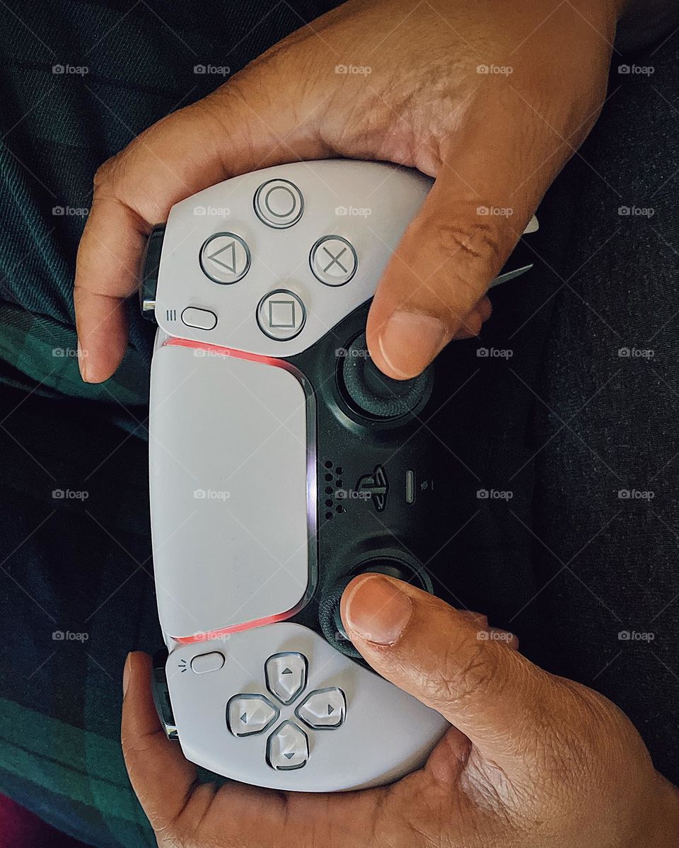 Woman holding PS5 game controller, playing PS5, hands holding controller, gaming console controller, gaming on PS5, woman’s hands holding gaming controller