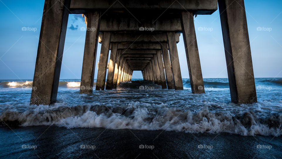 Under a pier during late day With ocean waves