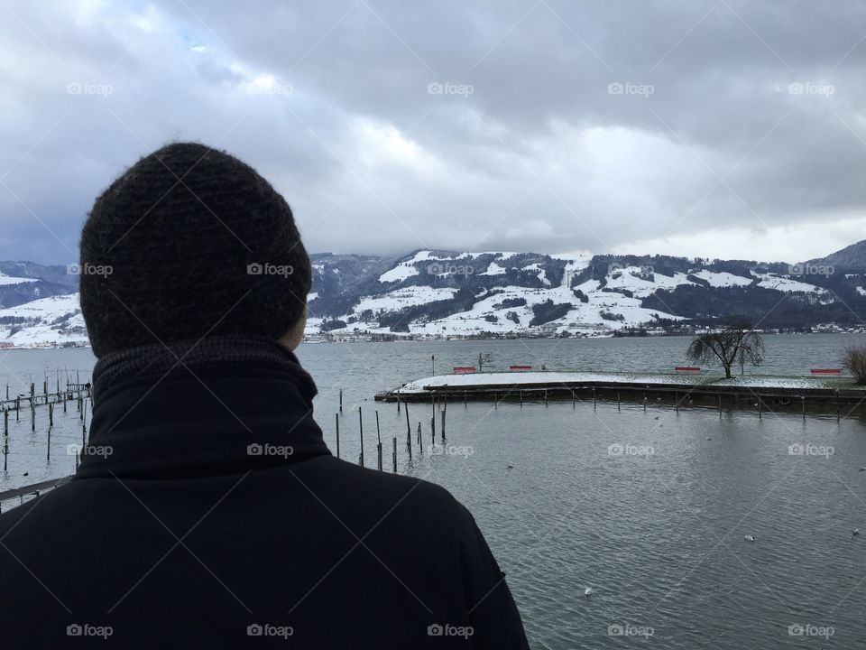 Man from behind admires the beautiful Lake view on a very cold Winter day.