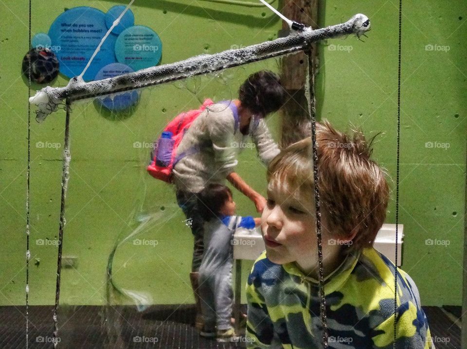 Boy Blowing Soap Bubbles. Experimenting With Soap Bubbles On A School Field Trip
