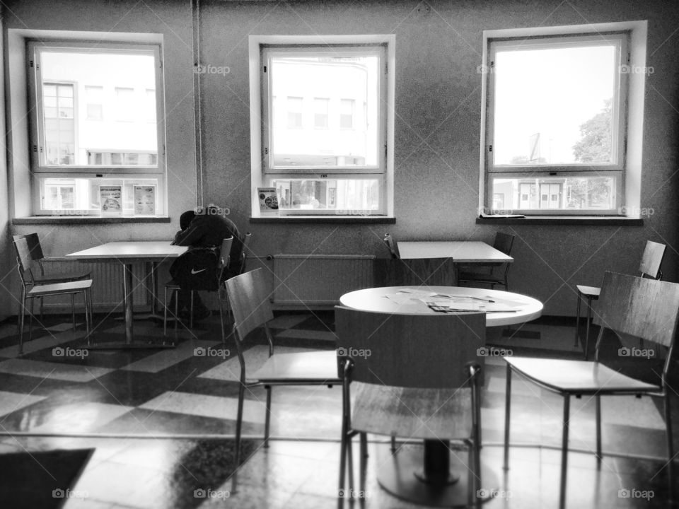 A long journey's day. Tired passenger sleeping at the table of bus station's cafeteria.