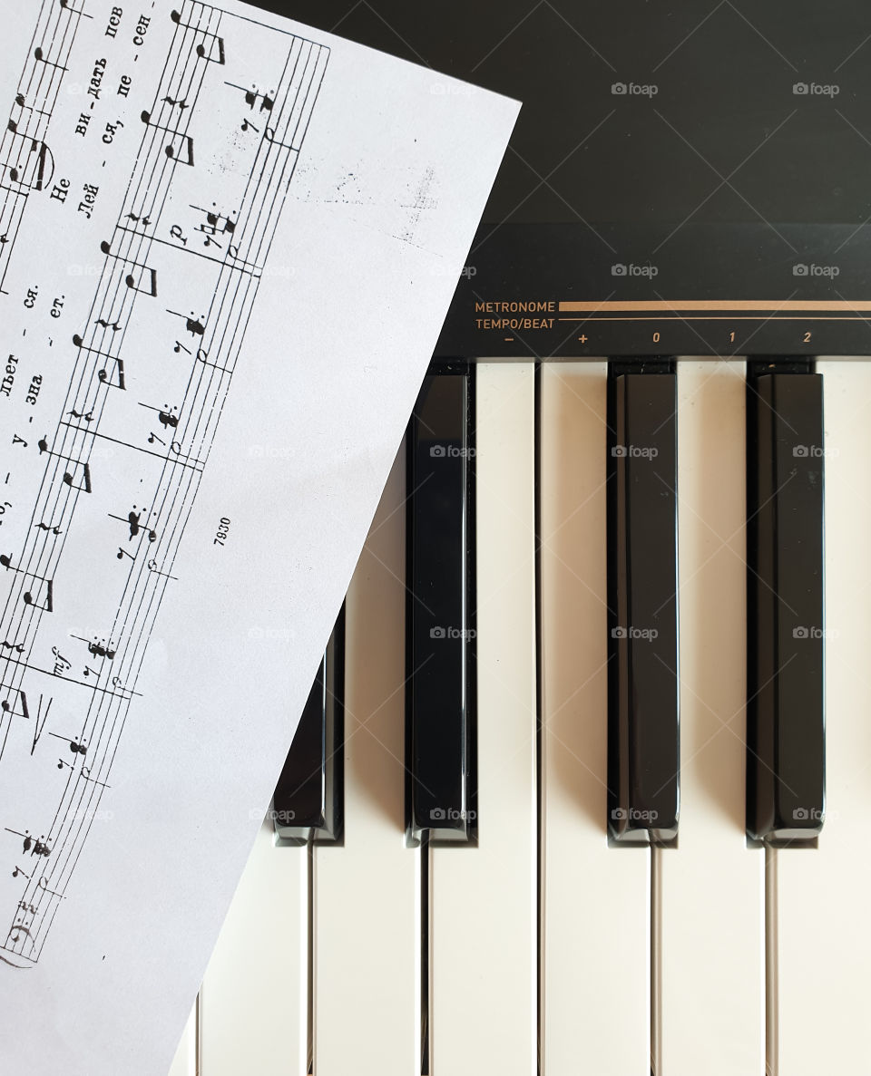 Musical instrument.  Black and white synthesizer keyboard keys with music sheet
