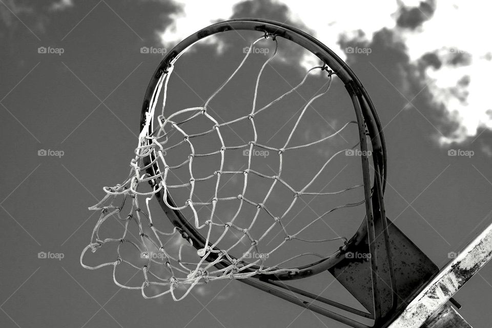 Black and white photo of a basketball net, view from below a basketball hoop, playing on the basketball court, monochrome basketball hoop