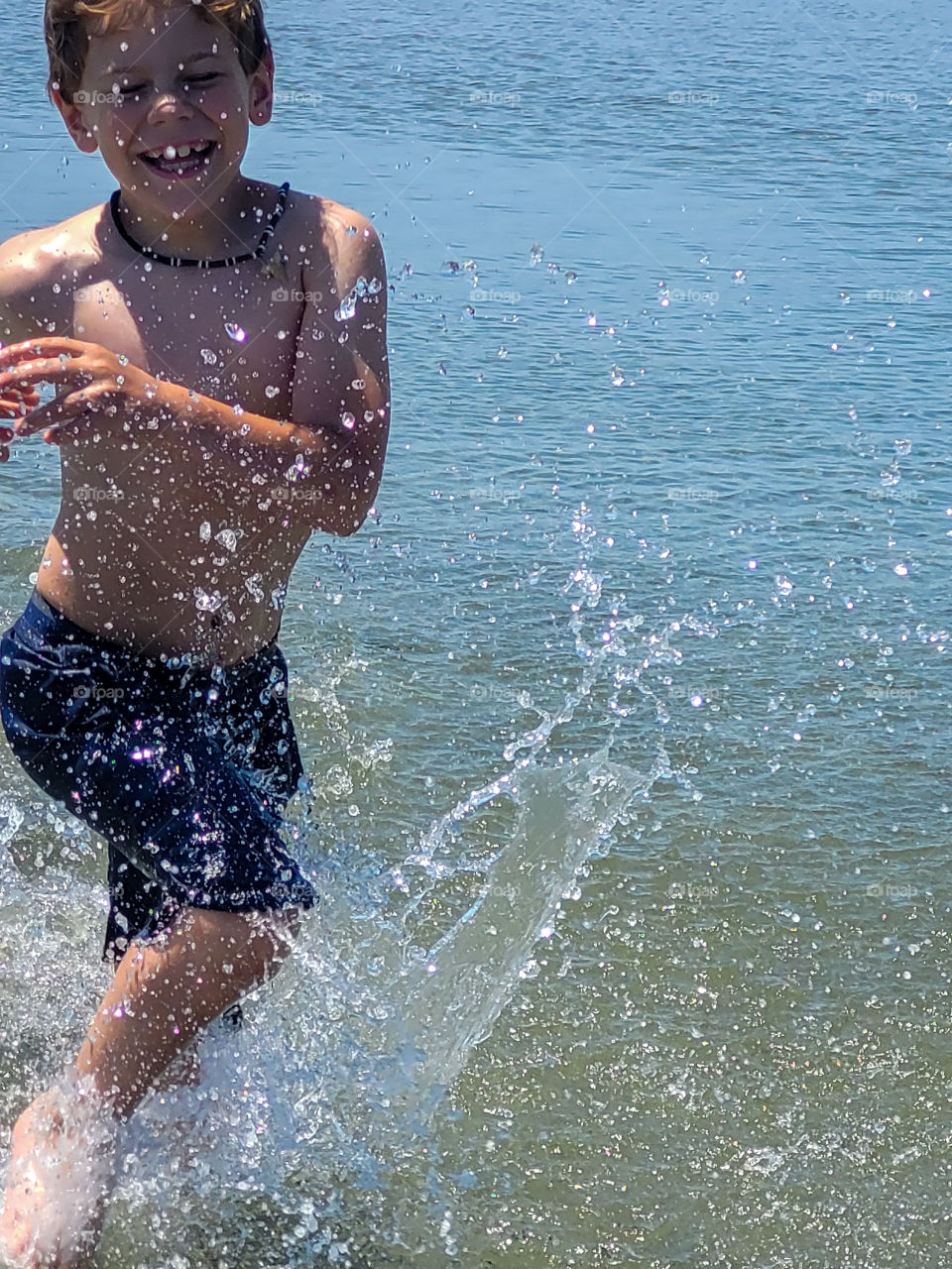 Boy splashing and smiling on the beach