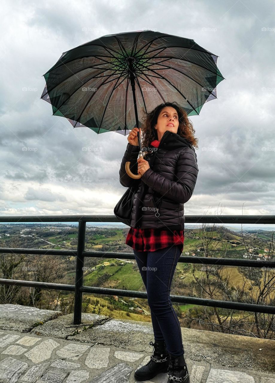 woman with umbrella in autumn clothes looks at the rain clouds