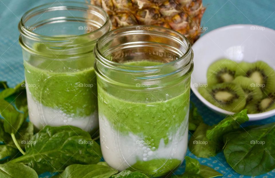 Fresh Fruit Smoothie -two spinach, kiwi, coconut milk and pineapple smoothies in pint canning jars on a turquoise tablecloth 