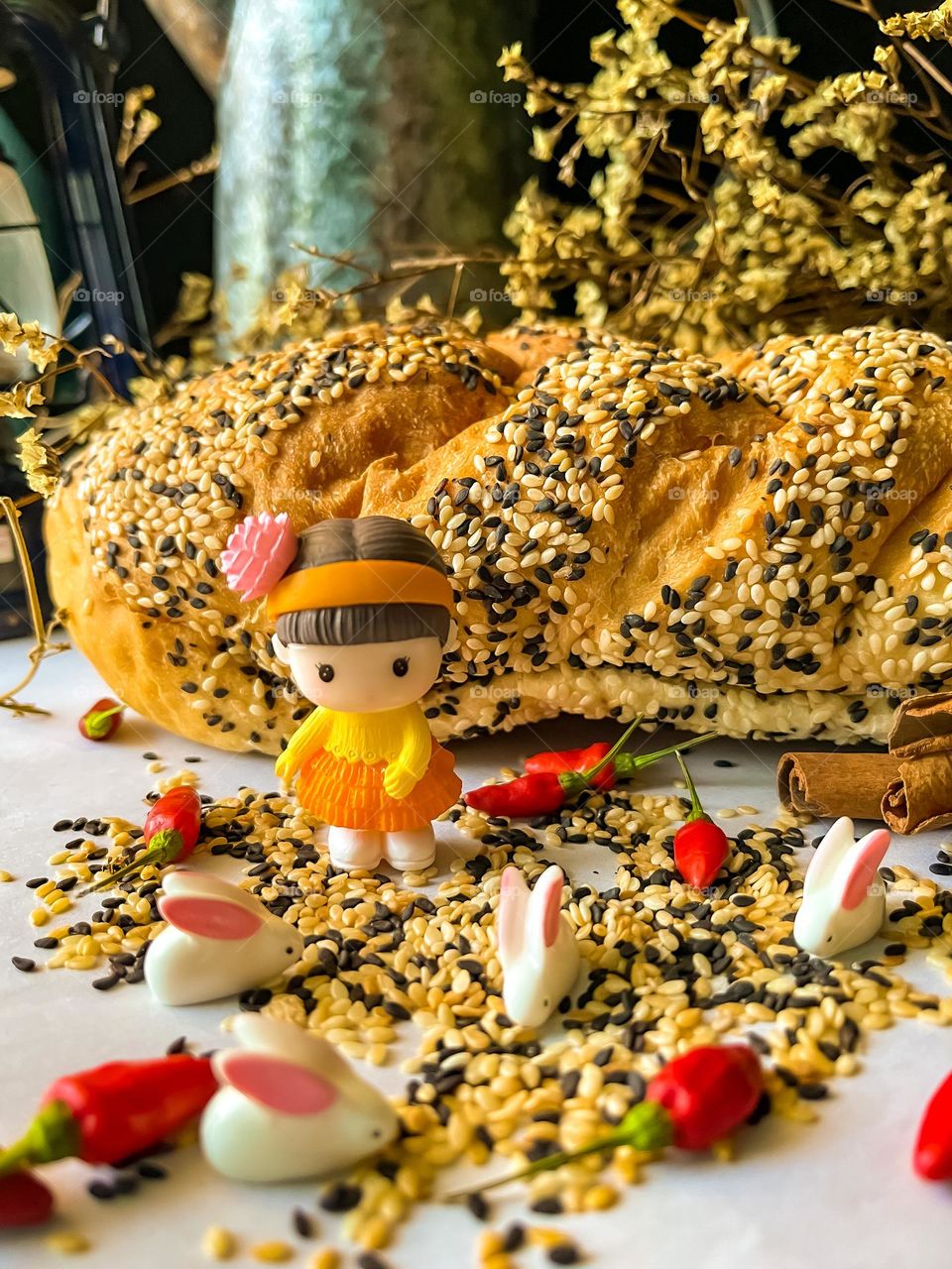 Cute miniature rabbits and a little girl on scattered sesame seed and bread in close up view