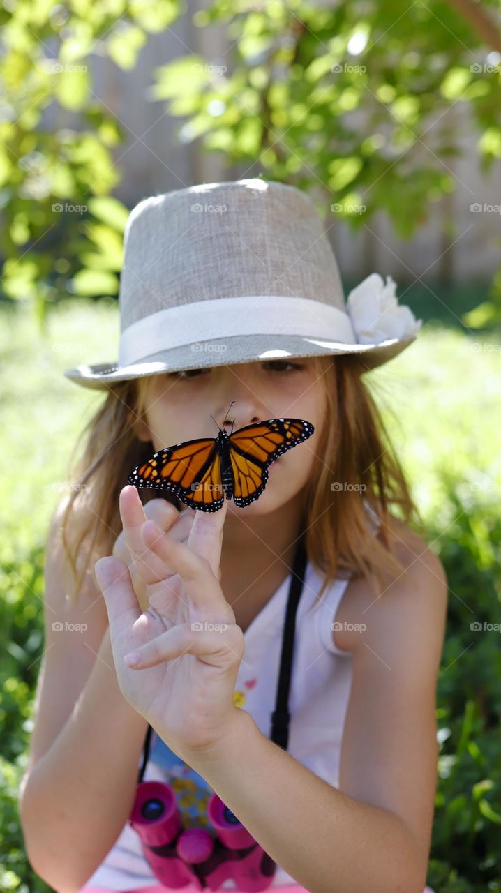 Young girl, exploring the butterfly landed on her finger
