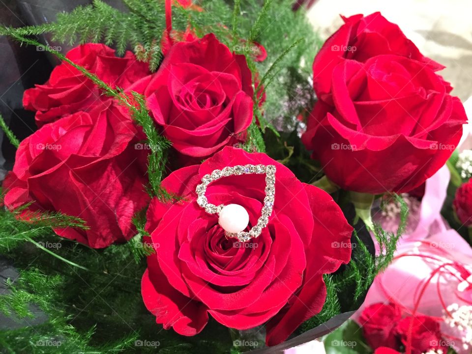 a bouquet of red roses with jewelry.