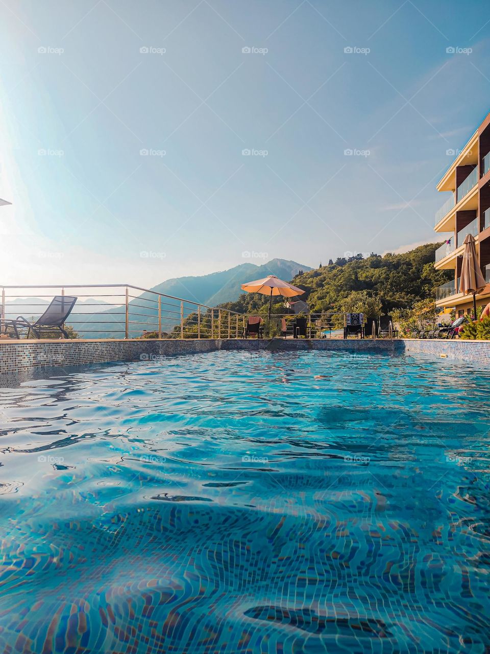 A pool in a countryside hotel, with the black mountains of Montenegro in the background.  Sun is about to set down. Amazing vacation place.