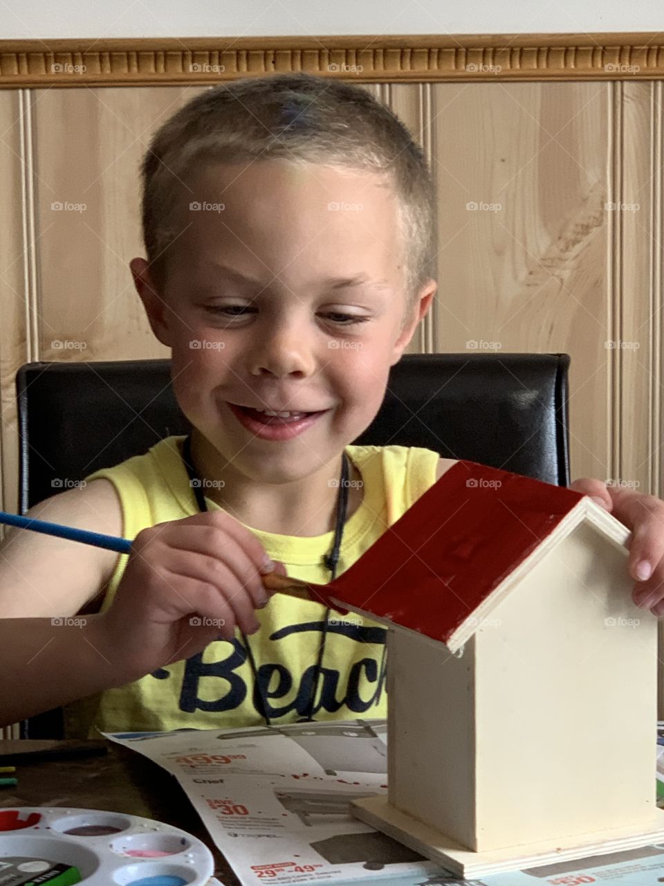 Boy painting a bird house 