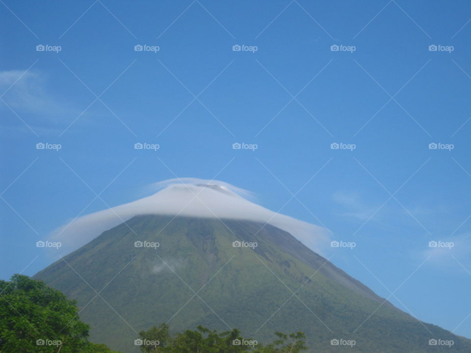 A thin cloud hangs over the top of the Arenal volcano in Costa Rica.