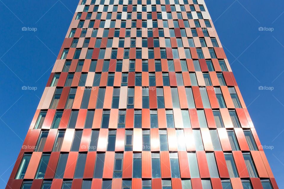 Tall colorful building with rectangle windows in sunlight 