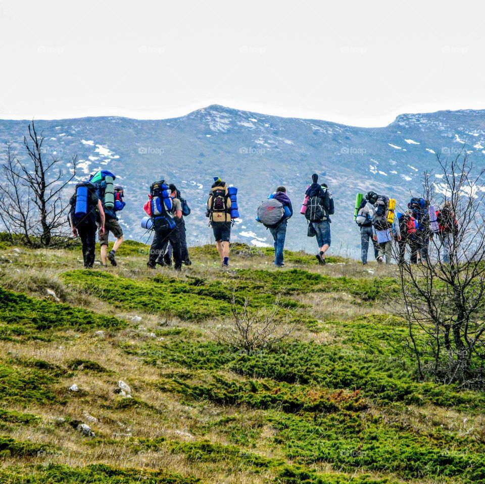 group of friends are walking along a mountain path