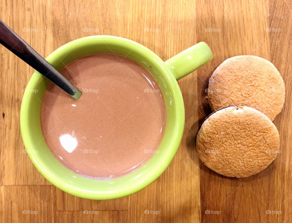 Hot cocoa in a green cup with cookies flat lay