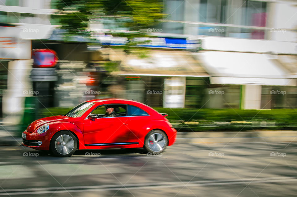Red VW Beetle passing . Volswagen passing in the center of Marbella, Spain 