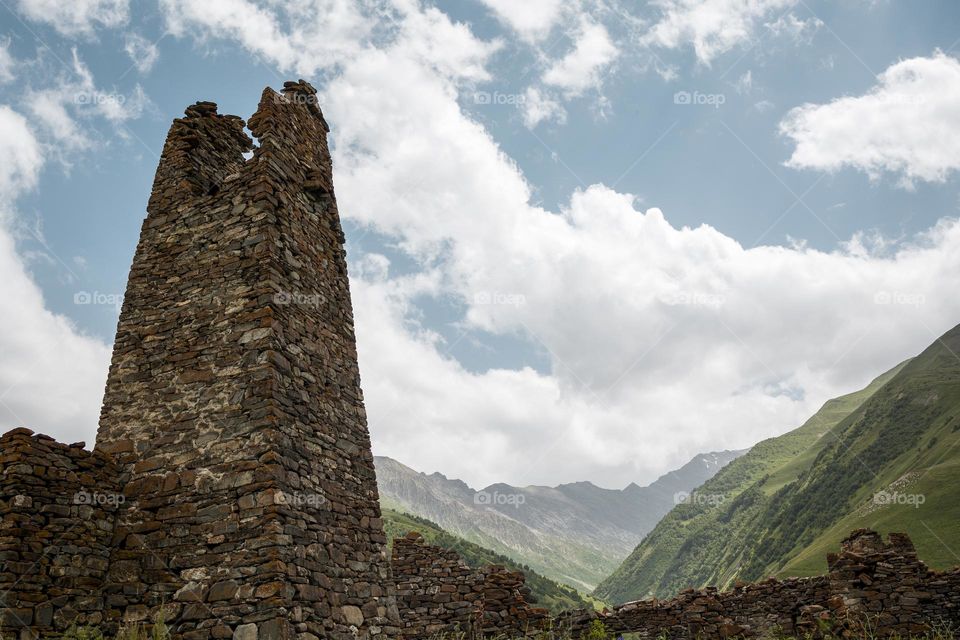 ancient stone watch tower on background of Caucasus Mountains.