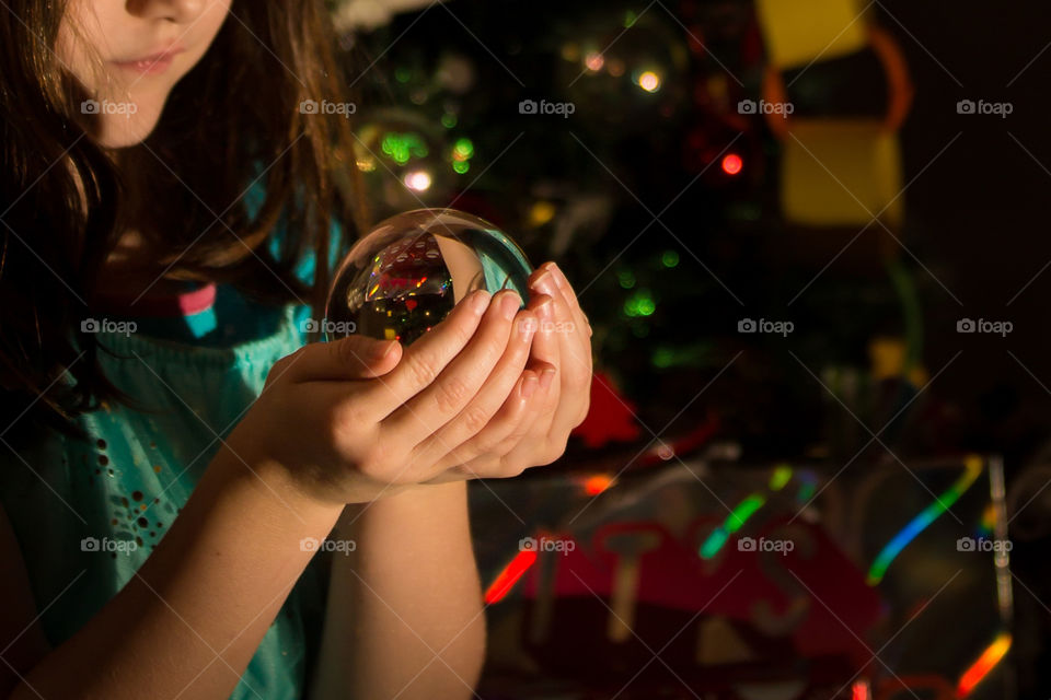 Such a special moment where my girl appreciates the magical feel of Christmas holding a glass ball with Christmas gifts reflecting in the ball.