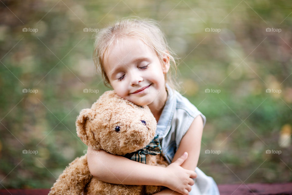 Little girl with blonde hair and teddy bear 