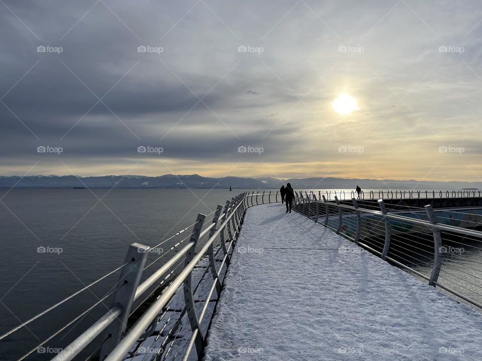 Walk on a snow covered breakwater in a cold winter morning 