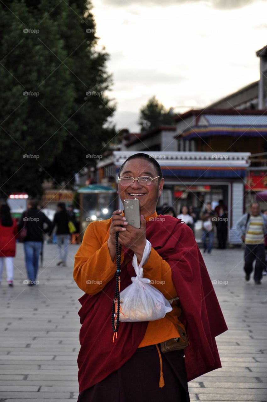 smiling buddhist monk taking pictures in the yard of buddhist monastery in Lhasa