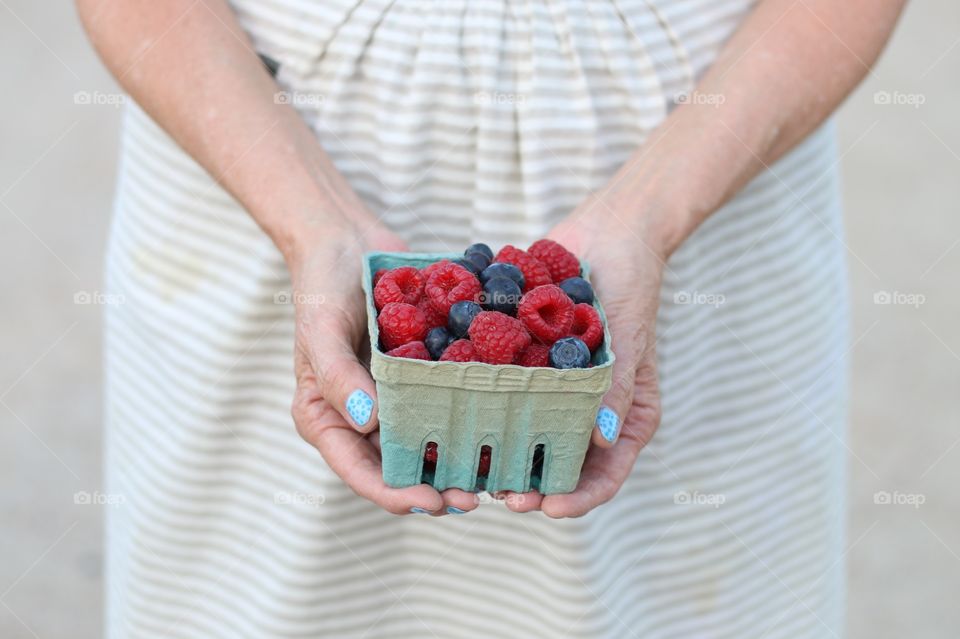 Woman holding raspberries and blueberries 