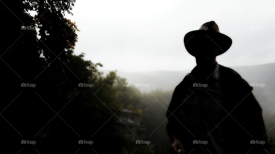 Silhouetted man overlooking a foggy mountainside.