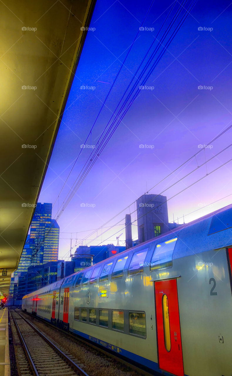 Belgian train waiting in the Brussels North railway station under a deep dark purple sunset sky in wintertime