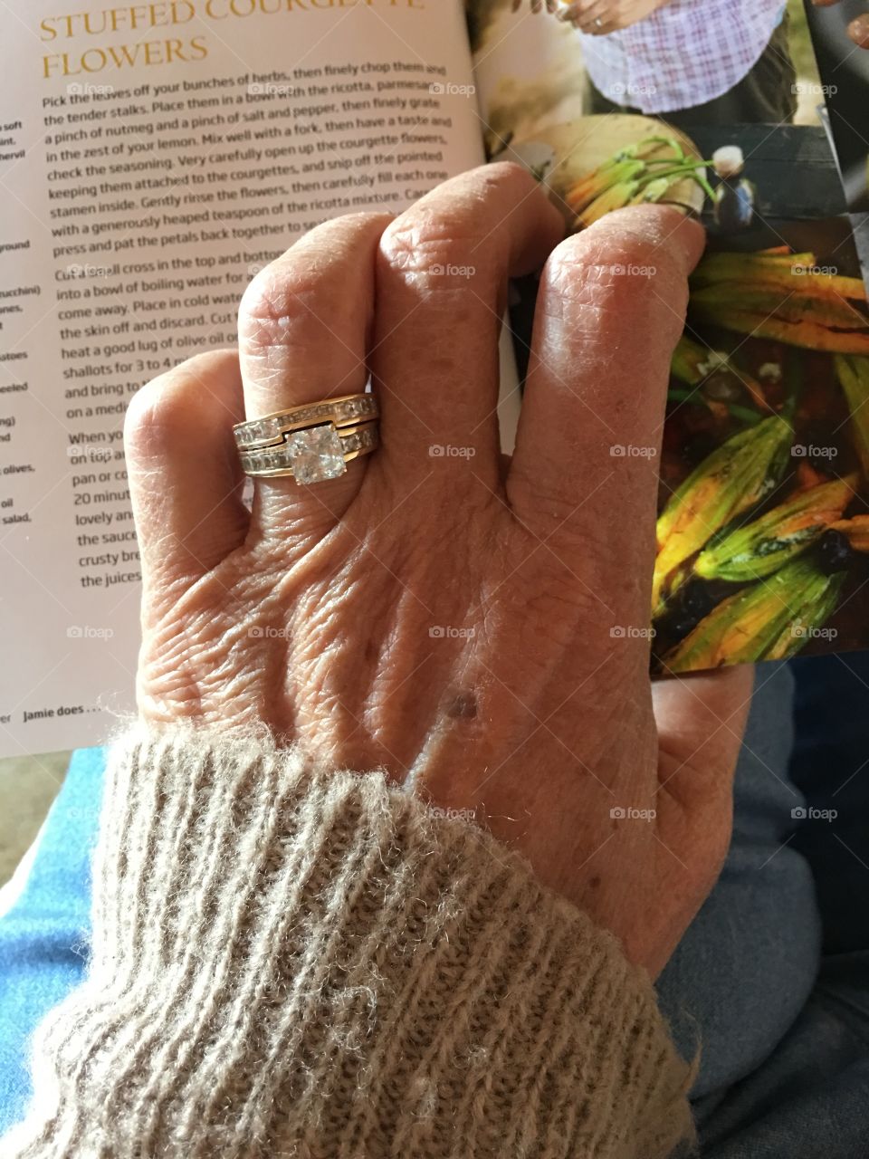 Ageing female left hand with wedding ring on a cookbook