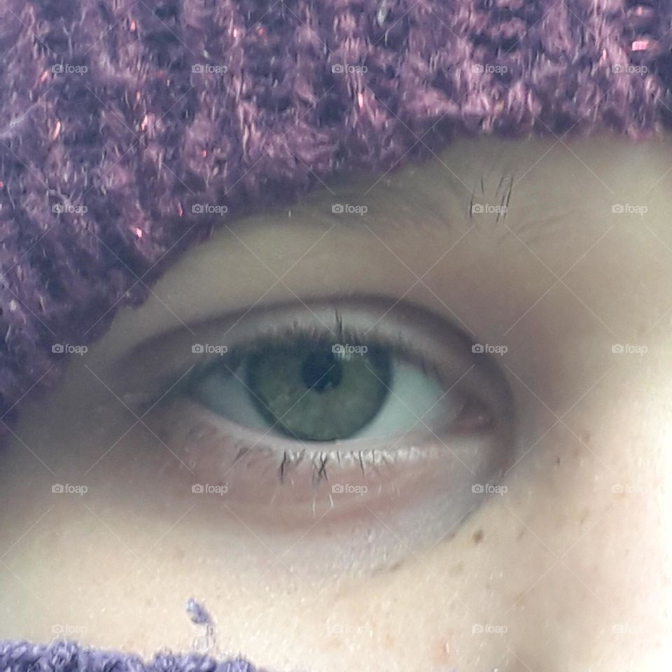 green eye of girl with purple hat and scarf