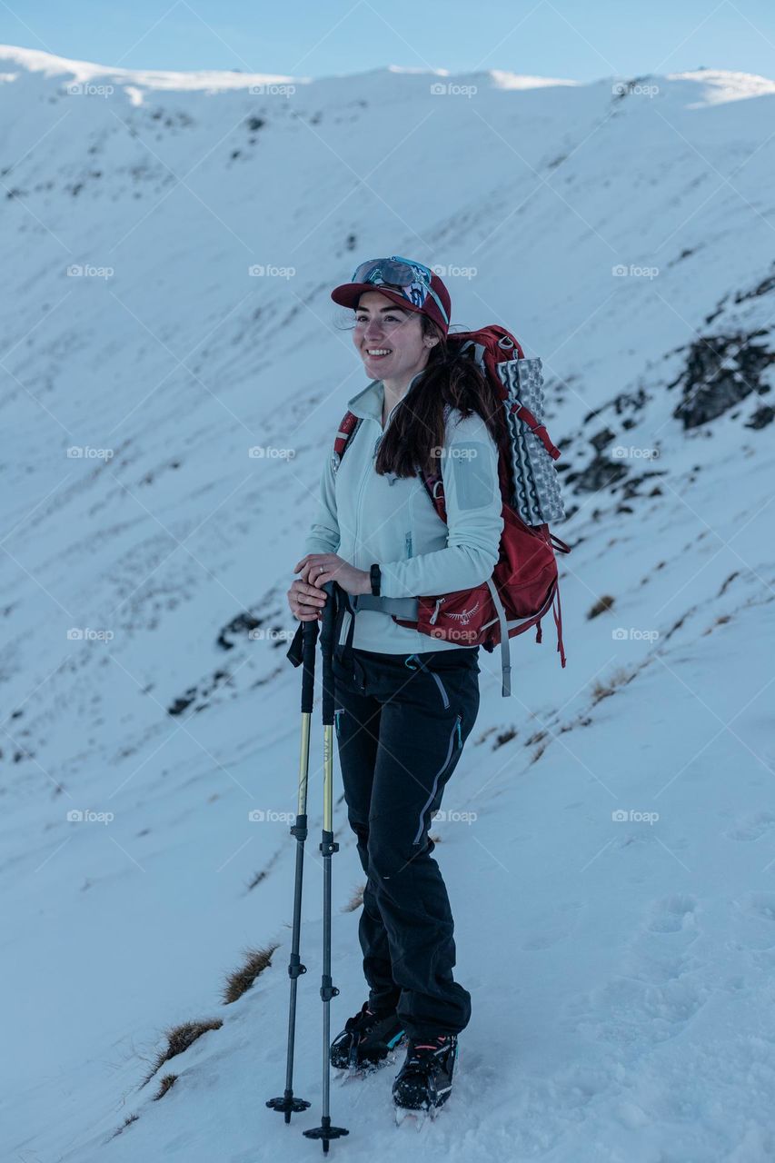Happy young woman, hiking in winter time in the mountains.
