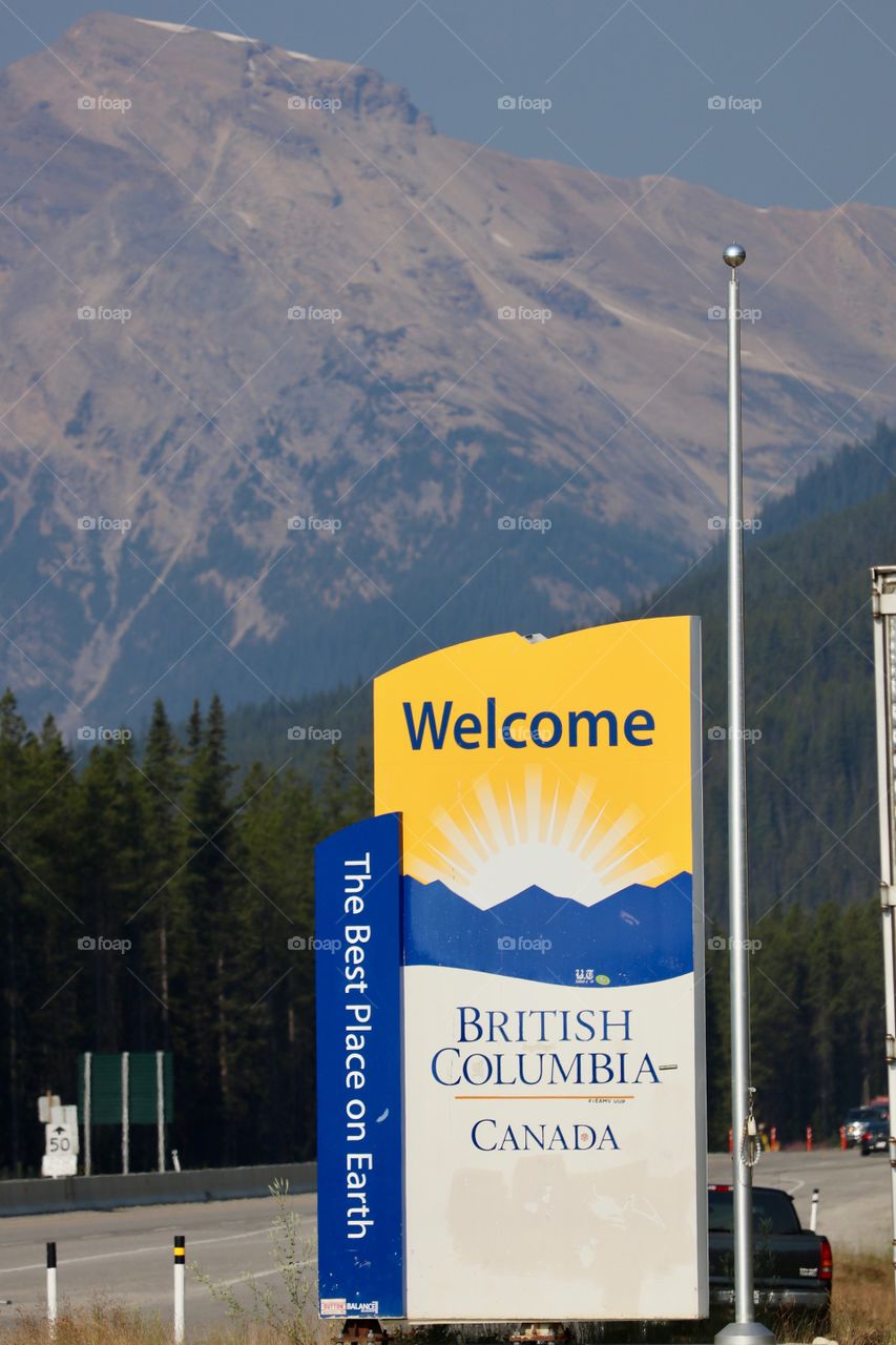 Welcome to British Columbia, sign on transcanada highway leaving Alberta in Canada's Rocky Mountains with view of snow capped mountains 