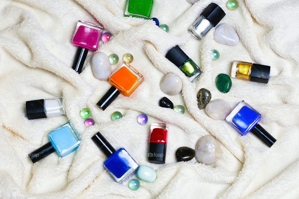 colourful nail polishes and stones scattered on a blanket