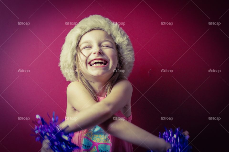 Portrait of little girl laughing with cross hand
